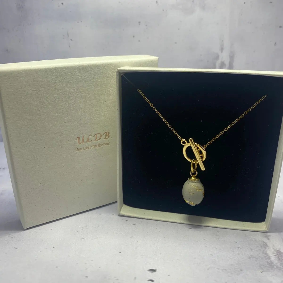 Collier Ovale Doré – Béton & Or Une Lueur de Bonheur